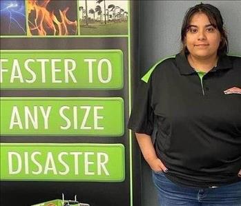 SERVPRO employee wearing a dark shirt standing next to a company display sign